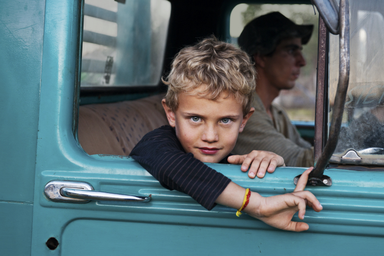 A young boy looks out the window of a truck - Steve McCurry